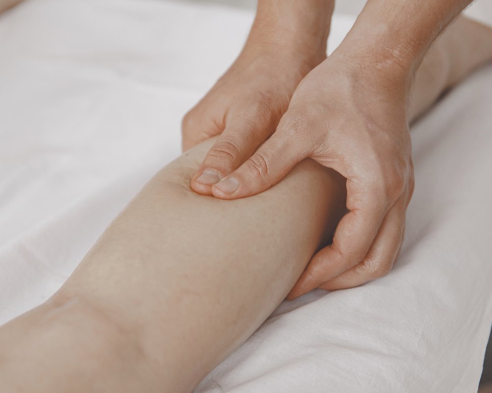 Esteticista realizando un masaje de drenaje en la pierna de una clienta